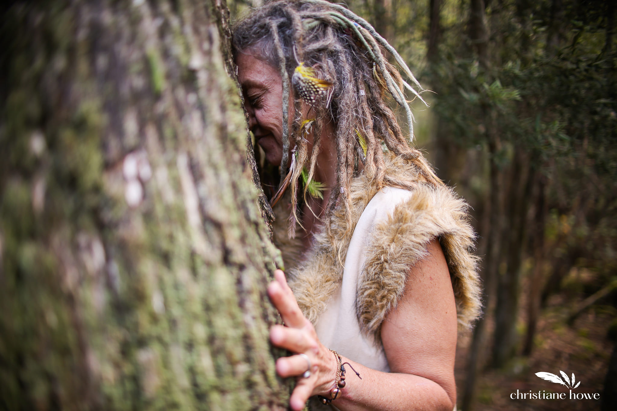 Teula Wylde resting against a tree in the forest